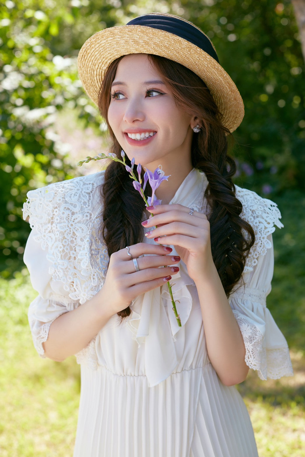 手に紫の花をもって 赤いネイルしてる女の子